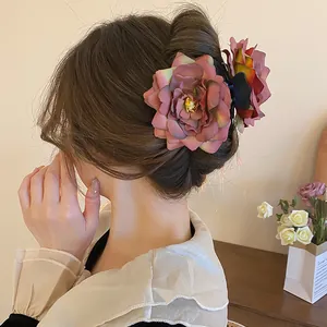 Détail d'une grande pince à cheveux en tissu rose fané utilisée dans un chignon élégant