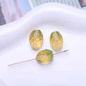Detailed view of yellow and green mini pineapple glass beads for DIY jewelry making.