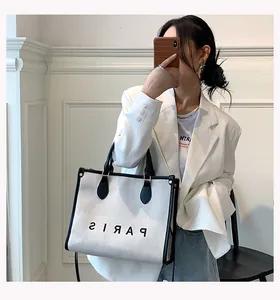 Detailed view of white canvas tote bag with black trim and Paris print lettering
