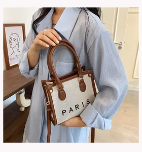 Detail shot of a stylish canvas tote bag with PARIS lettering and brown trim handles.
