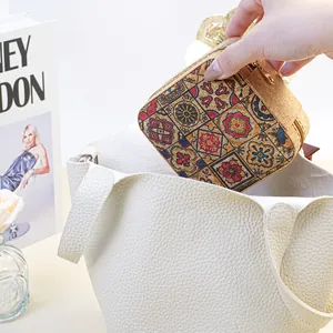 Exotic floral patterned cork jewelry box being placed into a white leather handbag