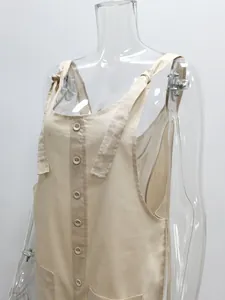 Detailed view of beige cotton linen overalls with tie straps and decorative buttons.