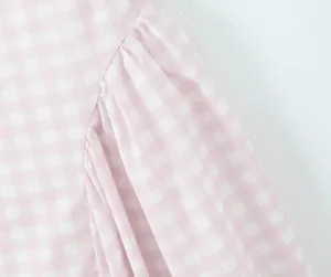 Close-up of pink and white checkered fabric with elegant pleated sleeve details.