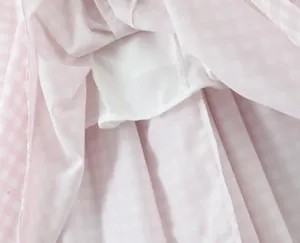 Close-up view of a pink gingham summer dress showing the white inner lining and stitching