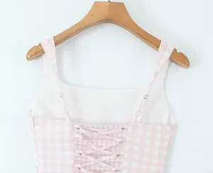 Close-up detail of a pink and white gingham dress featuring a lace-up back and thin straps
