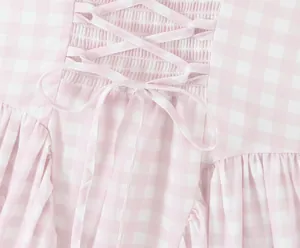 Detailed macro view of pink and white gingham dress showing back lacing and smocking