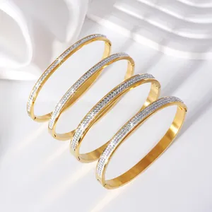 Detailed macro view of four gold-plated stainless steel bangles with sparkling crystals.