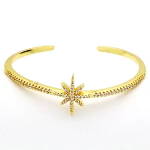 Elegant gold cuff bracelet with a sparkling crystal-encrusted starburst center detail.
