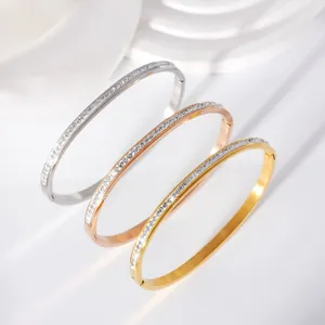 Detail of three stainless steel bangles in gold, rose gold and silver with inlaid stones