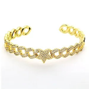 Close-up of a gold-plated Cuban link open cuff bracelet featuring a paved crystal star.