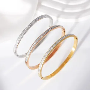 Detail view of three stainless steel pavé crystal bangles in gold, rose gold and silver