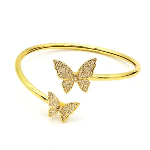 Detail view of a gold-plated open cuff bracelet featuring two sparkling butterfly motifs.