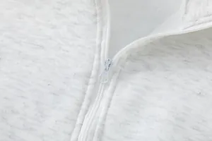 Macro di una cerniera bianca liscia sul colletto di una felpa grigio chiaro melange.
