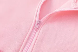 Dettaglio ravvicinato della cerniera rosa su una morbida felpa casual foderata in pile.