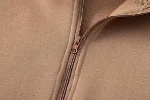 Primo piano della trama del tessuto in pile marrone e della zip della felpa casual in tinta