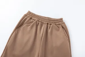 Primo piano della fascia elastica in vita e della tasca laterale dei pantaloni marroni.