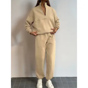 Tuta beige a due pezzi alla moda con colletto a zip e pantaloni coordinati.