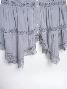 Detailed close-up showing lace embroidery and buttons on an elegant lavender linen top