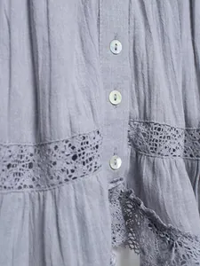 Macro detail view of a lavender purple blouse featuring pearl buttons and floral lace trim