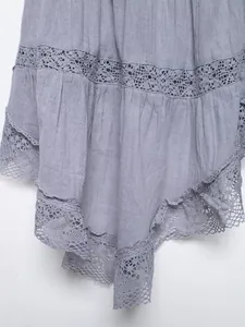 Detailed close-up of intricate lace embroidery and textured fabric on a lavender top