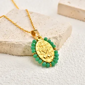 Detailed macro view of vintage gold-plated oval pendant with green beads and cross motif