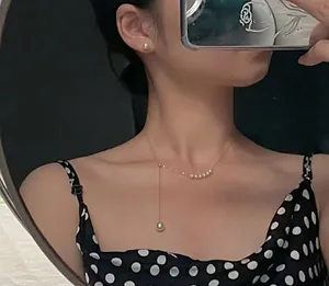 Detail view of a model wearing a mermaid tear pearl Y-necklace with silver chain.