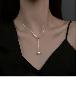 Élégant collier à pampilles doré avec des perles blanches porté par un mannequin féminin