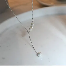 Élégant collier lariat en perles argentées avec pampille réglable sur fond marbre