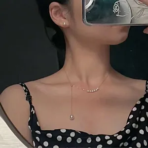 Elegant mermaid tear pearl necklace with Y-chain and matching stud earrings on model