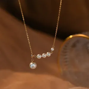 Élégant collier de perles avec chaîne en or et pendentif de perle en lumière chaude.