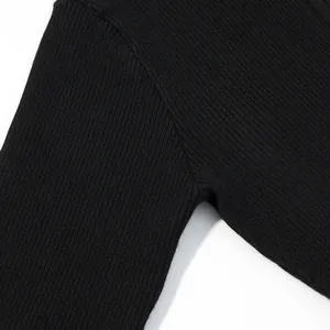 Vista dettagliata della trama in maglia a coste nera e delle cuciture della manica.
