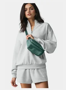 Stylish woman wearing a light gray oversized half-zip sweatshirt and casual short set
