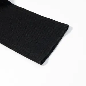 Dettaglio del polsino in maglia a costine nere di una tuta elegante da donna