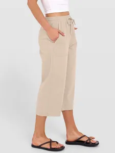 Detail view of beige wide-leg linen pants featuring elastic drawstring waist and pockets