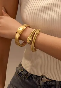 Detailed close-up of a golden elastic snake bracelet with green zircon eyes on a wrist
