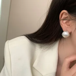 Elegant textured silver-finish stud earring worn by model, showing pleated metal detail