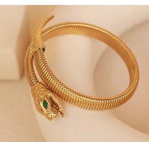 Close-up of golden snake bracelet with green zircon eyes and flexible spiral design