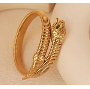 Close-up of golden snake wrap bracelet with green zircon eye and ribbed texture