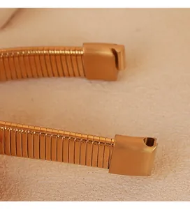 Macro detail of a gold flexible wrap-around snake bracelet showing metallic texture