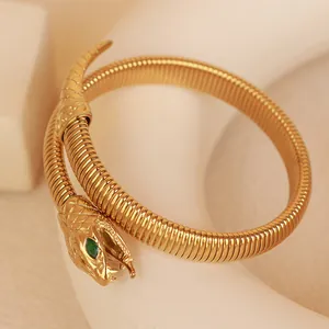 Elegant gold-tone elastic snake wrap bracelet with green zircon eye on warm background
