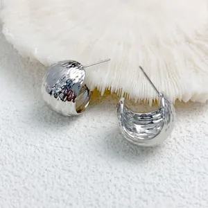 Macro detail of minimalist geometric hammered silver hoop earrings with organic texture