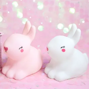 Lindas luces nocturnas en forma de conejo rosa y blanco con luz ambiental suave de cuarto.