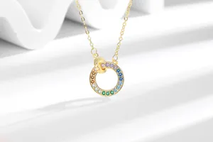 Detailopname van gouden dubbele ring ketting met regenboogkristallen op witte achtergrond