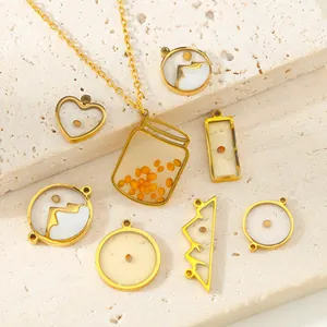 Detailed view of gold stainless steel mustard seed pendants on a travertine slab