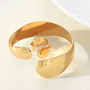 Close-up of polished gold water drop cuff bracelet and matching adjustable ring set.