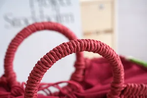 Primer plano de las asas tejidas rojas de un bolso de playa de paja sandía