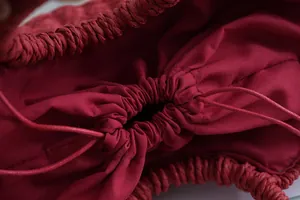 Primer plano del forro de tela roja con cordón ajustable dentro de un bolso de paja.