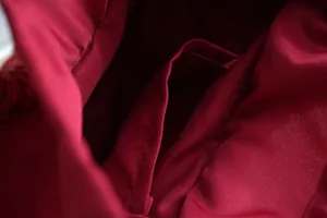 Primer plano del forro interior de tela rojo oscuro con bolsillo para bolso de paja