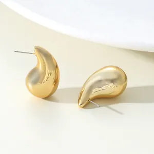 Detailed macro view of golden waterdrop-shaped stud earrings with polished finish