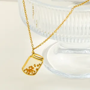 Close-up detail of a gold stainless steel necklace with a clear mustard seed jar pendant
